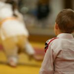 child in pink long sleeve shirt and yellow pants standing on brown wooden floor