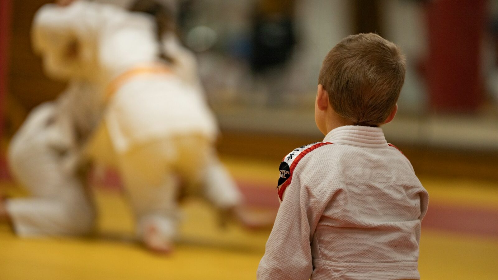 child in pink long sleeve shirt and yellow pants standing on brown wooden floor