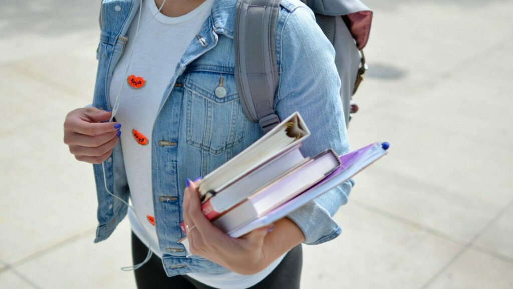 woman wearing blue denim jacket holding book